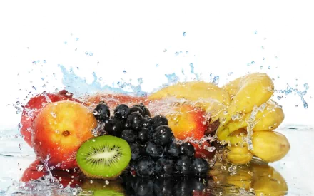A vibrant assortment of fresh fruit, including apples, bananas, blueberries, and kiwi, splashes into water, creating a refreshing and colorful HD desktop wallpaper.