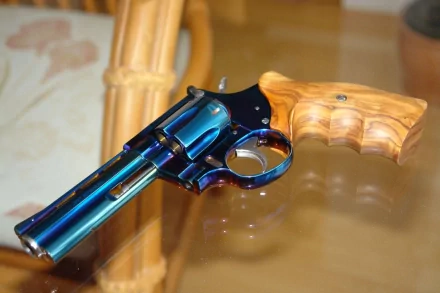HD desktop wallpaper of a man-made revolver with a polished wooden grip resting on a glossy surface.