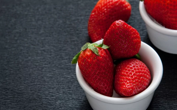 HD PC desktop wallpaper featuring fresh, vibrant strawberries in white bowls on a dark textured surface, highlighting the rich red color and natural texture of the fruit.