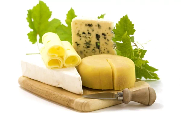 HD PC desktop wallpaper featuring a variety of cheeses, including blue cheese, gouda, and brie, arranged on a wooden board with green leaves.