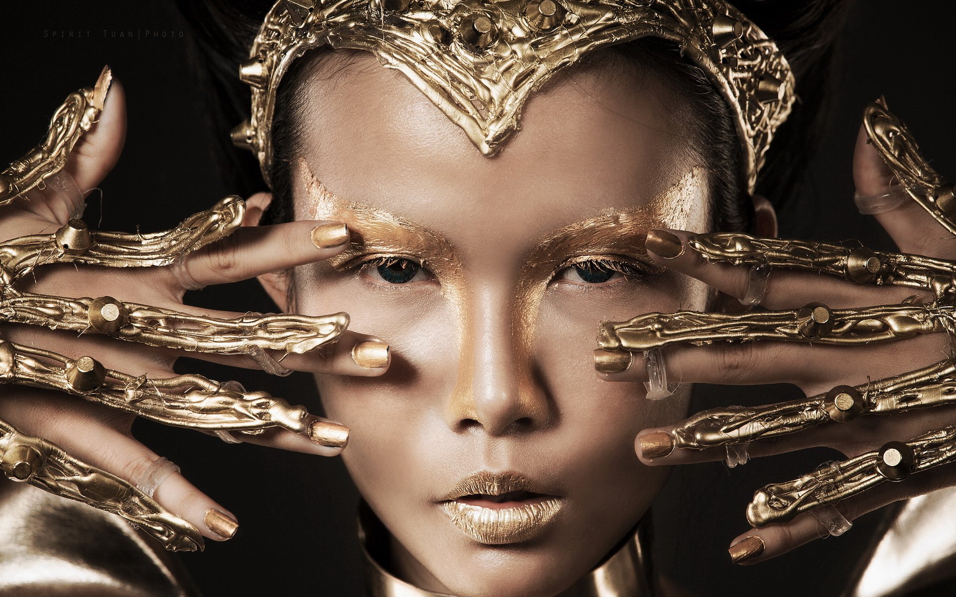 HD PC desktop wallpaper featuring a woman model with metallic gold makeup and intricate gold hand accessories framing her face against a dark background.