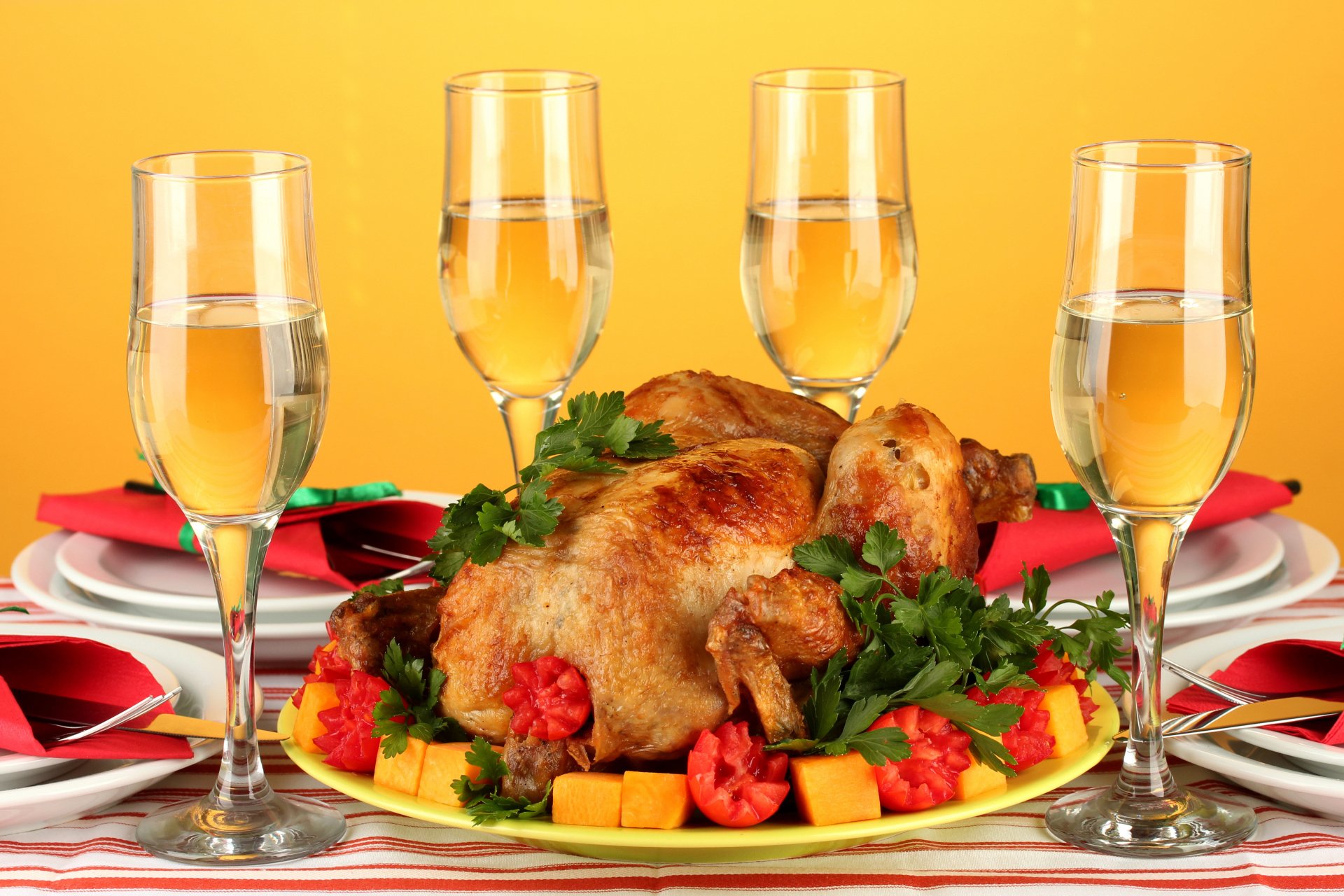 4K Ultra HD desktop wallpaper of a roasted whole chicken garnished with vegetables and surrounded by four filled wine glasses on a vibrant yellow background.