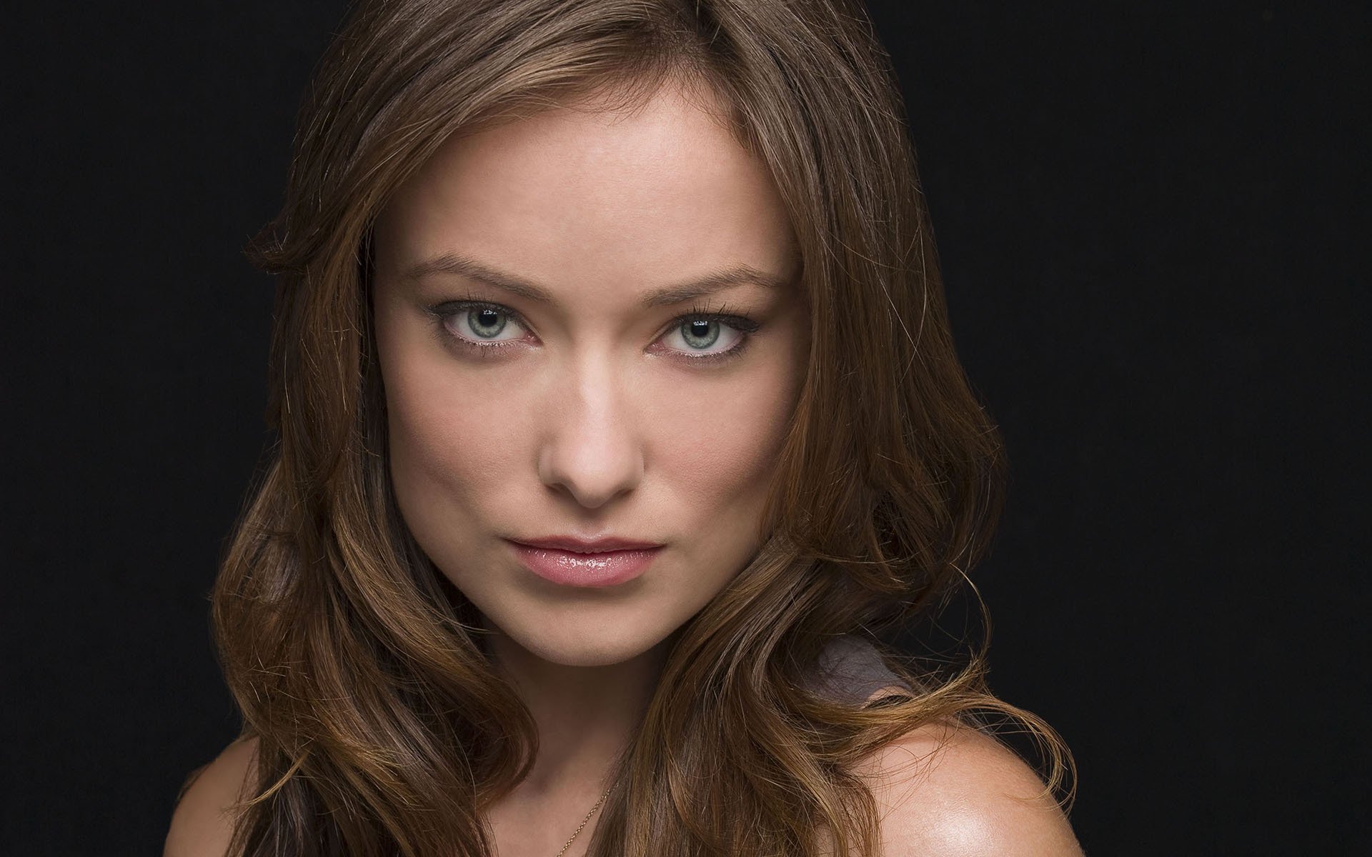 HD PC desktop wallpaper featuring a close-up portrait of celebrity Olivia Wilde with soft lighting against a dark background.