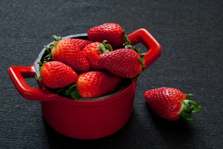 A vibrant 4K Ultra HD desktop wallpaper featuring fresh, ripe strawberries in a small red pot against a dark background.