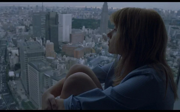 HD desktop wallpaper featuring a contemplative scene from the movie Lost In Translation, showing a woman gazing out over a sprawling cityscape at dusk.