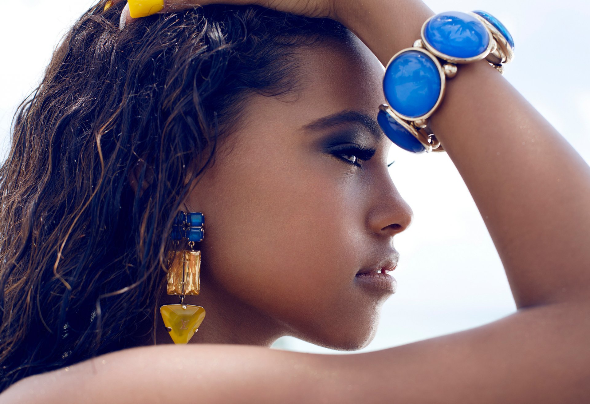 HD desktop wallpaper featuring a woman model adorned with vibrant earrings and a chunky blue bracelet, posing against a soft, blurred background.