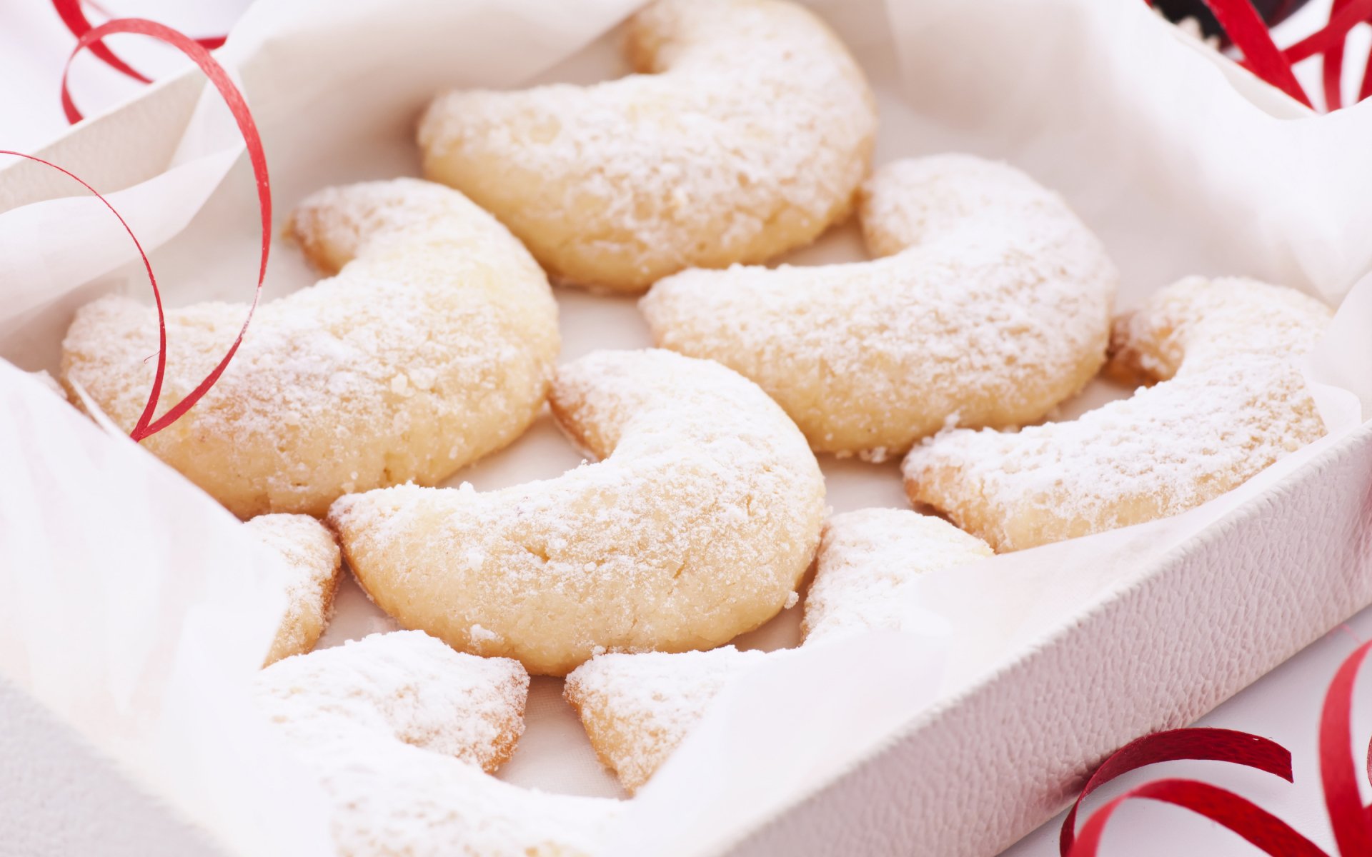 HD desktop wallpaper of crescent-shaped powdered sugar cookies arranged in a white box, highlighting food and baking themes.