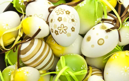 A vibrant collection of decorated Easter eggs in various shades of green and white, adorned with ribbons and floral patterns. This HD wallpaper captures the festive spirit of the holiday.