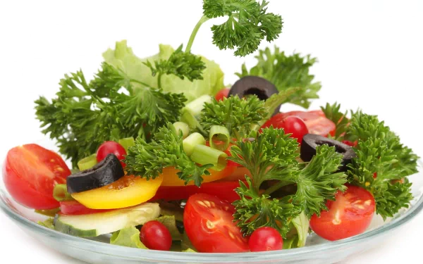 HD PC desktop wallpaper featuring a fresh, colorful salad with cherry tomatoes, black olives, lettuce, and parsley on a clear plate against a white background.