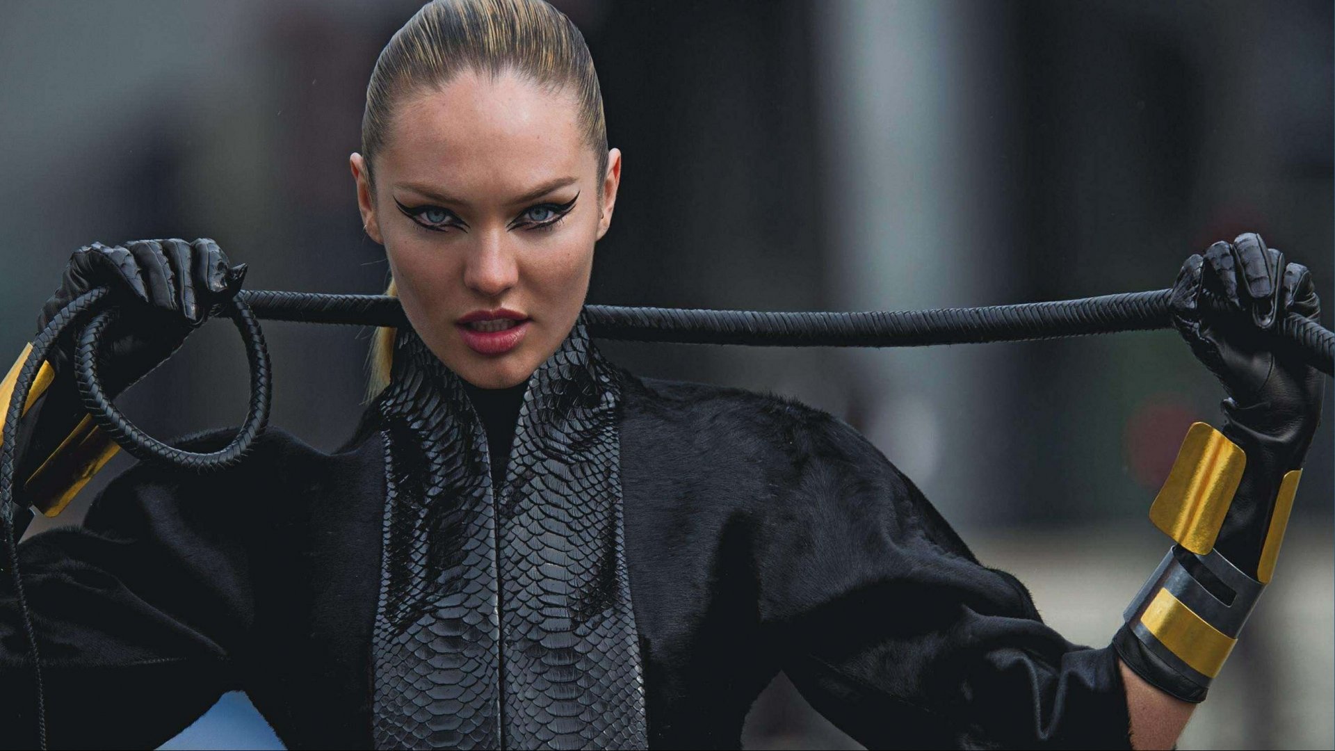 A striking HD desktop wallpaper featuring a woman in a sleek black outfit, holding a whip with fierce expression, showcasing bold fashion and attitude.