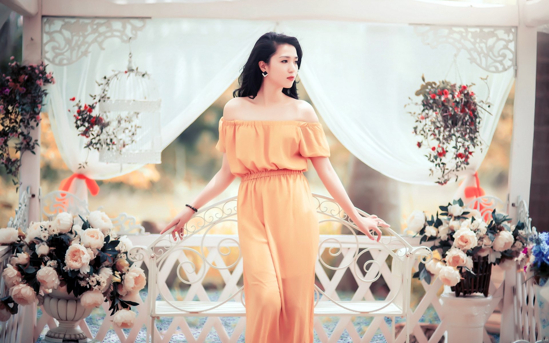 HD desktop wallpaper featuring an Asian woman in a yellow dress standing gracefully among floral arrangements and white drapery.