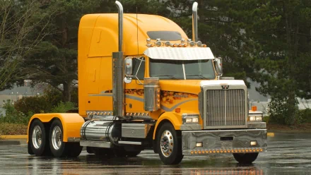 HD desktop wallpaper featuring a bright yellow Western Star truck parked on a wet surface with trees in the background.