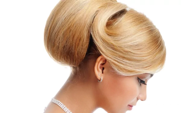 A woman with elegant, styled blonde hair is captured in profile, showcasing a sophisticated updo against a clean, white background. This makes for a striking HD desktop wallpaper.