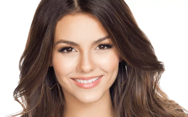A vibrant HD desktop wallpaper featuring celebrity Victoria Justice, showcasing her warm smile and flowing hair against a clean white background.