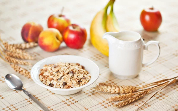 A still life featuring a bowl of muesli surrounded by fresh apples, a banana, wheat stalks, and a small jug of milk, creating a vibrant breakfast scene.