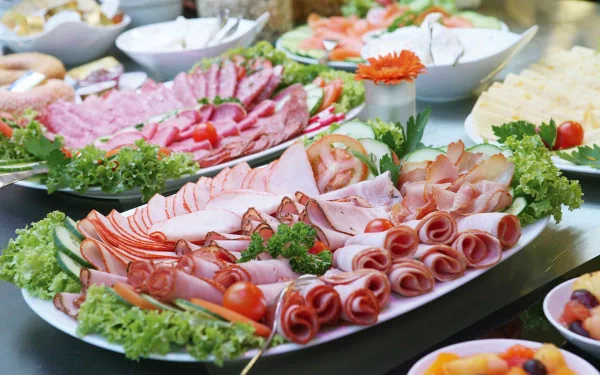 A vibrant display of assorted meats arranged beautifully on platters, surrounded by fresh greens and garnishes, creating an appetizing feast for a desktop wallpaper.