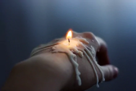 A close-up shot of a hand with a candle melting wax, creating an artistic composition. This image serves as a striking 4K Ultra HD desktop wallpaper and background.