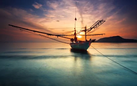 HD PC desktop wallpaper of a boat anchored on calm water at sunset, with a colorful sky and distant land in the background.