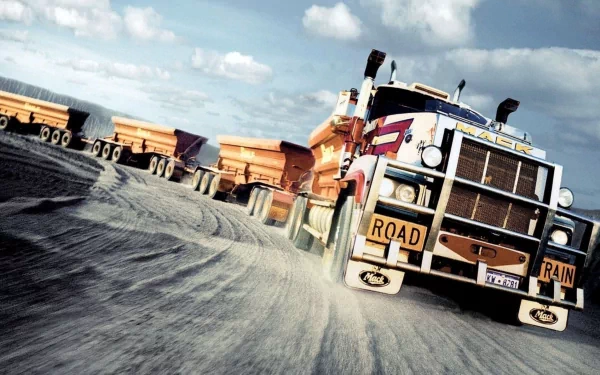 HD desktop wallpaper featuring a powerful Mack Trucks vehicle driving on a dirt road with a ROAD TRAIN sign under a cloudy sky.