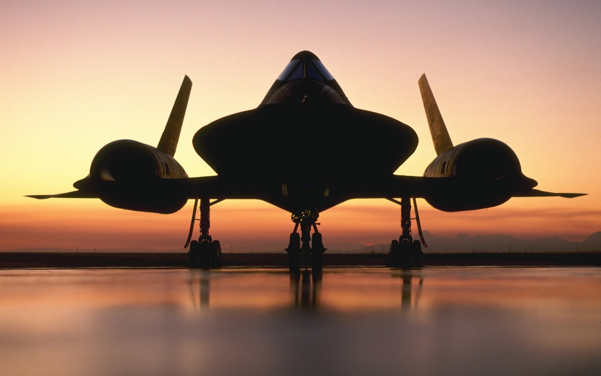 Silhouetted Lockheed SR-71 Blackbird on a runway at sunset, captured in a high-definition military-themed desktop wallpaper.