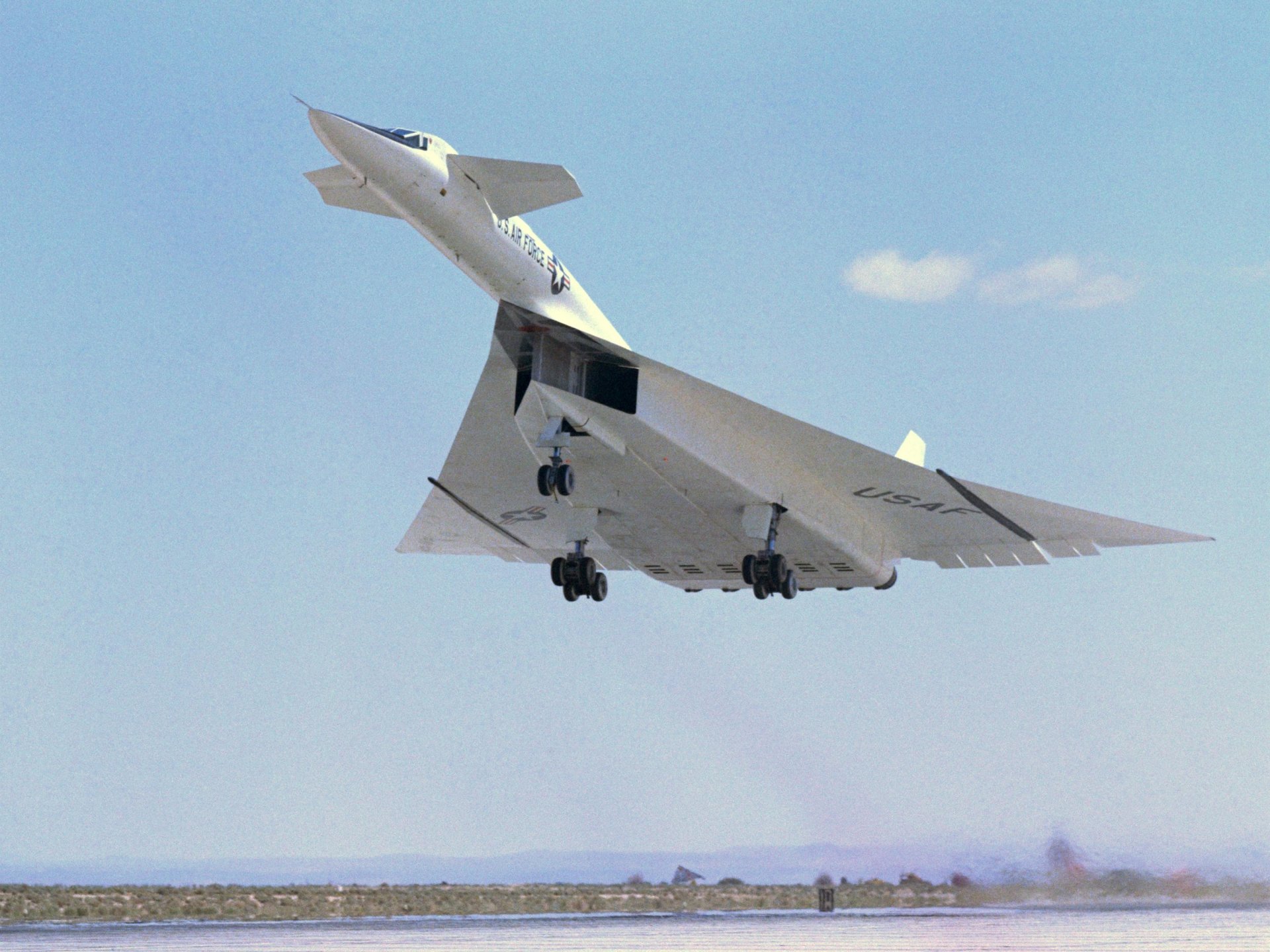 Military North American XB-70 Valkyrie in flight over a clear blue sky, close-up view — 2K Quad HD PC desktop wallpaper/background.