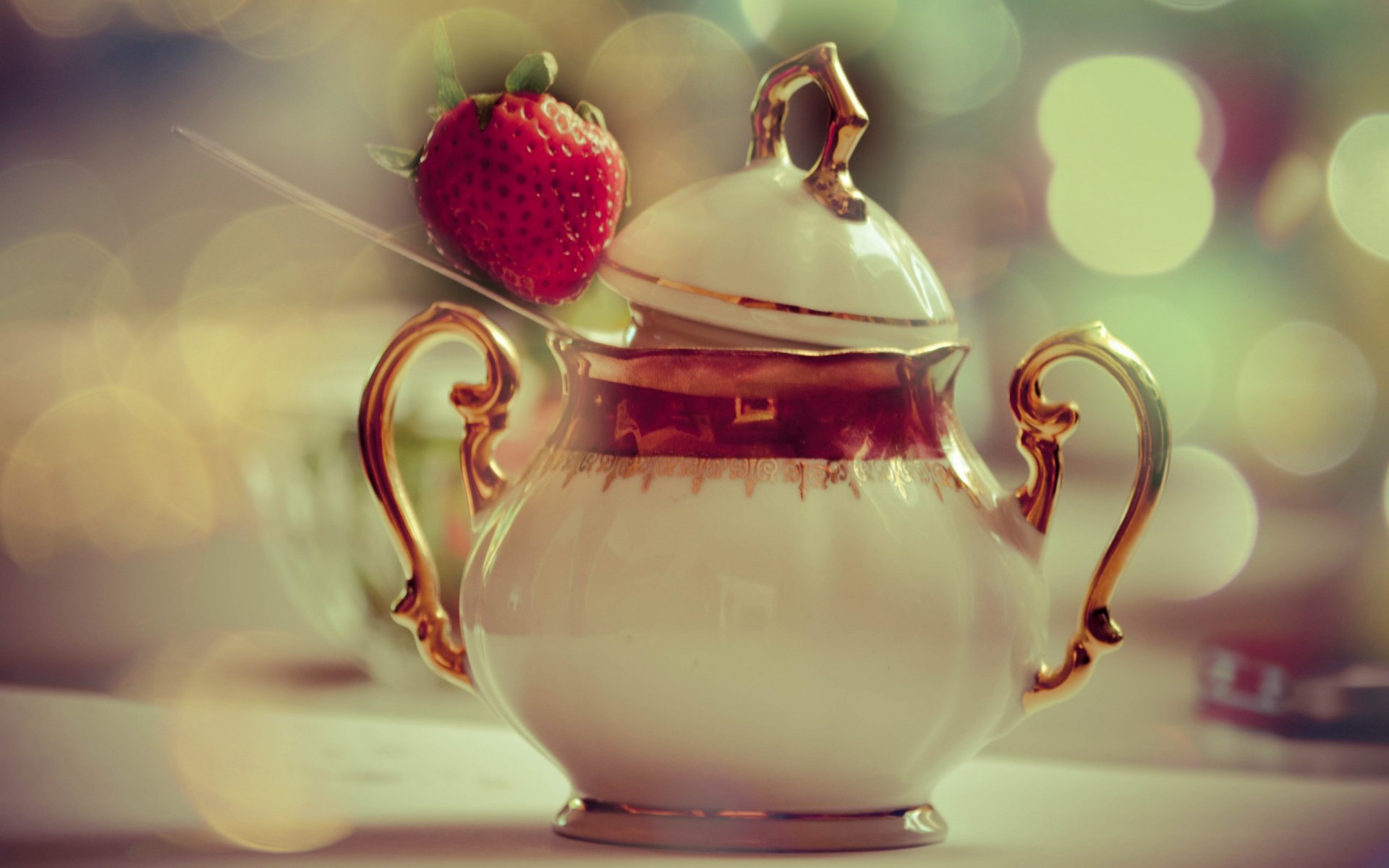 HD PC desktop wallpaper featuring a close-up of a porcelain sugar bowl with gold handles and a fresh strawberry perched on top, set against a soft, bokeh background.