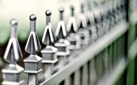 Close-up of a man-made metal fence with pointed finials, captured in sharp focus, presented as an HD PC desktop wallpaper and background.