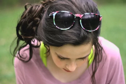 Close-up of a woman with dark hair styled in a loose updo, wearing floral sunglasses on her head, captured in a 4K Ultra HD PC desktop wallpaper background.
