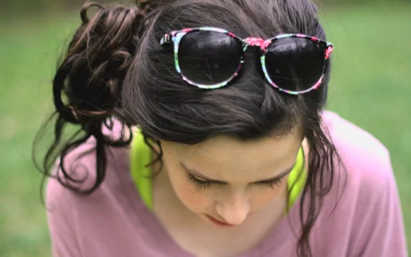 Close-up of a woman with dark hair styled in a loose updo, wearing floral sunglasses on her head, captured in a 4K Ultra HD PC desktop wallpaper background.