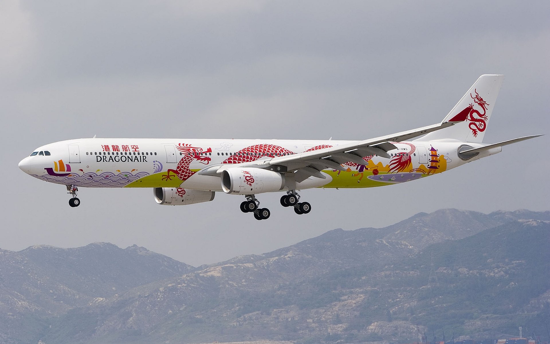 HD desktop wallpaper featuring a large aircraft with colorful dragon-themed artwork flying over mountainous terrain.