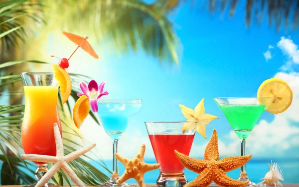 HD desktop wallpaper featuring colorful cocktails garnished with fruit and flowers, arranged with starfish on a tropical beach background under a bright blue sky.