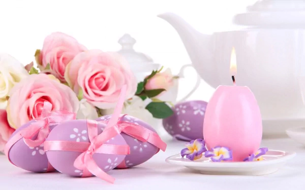 Easter-themed HD wallpaper featuring pink roses, decorated eggs with ribbons, and a lit candle in front of a teapot on a white background.