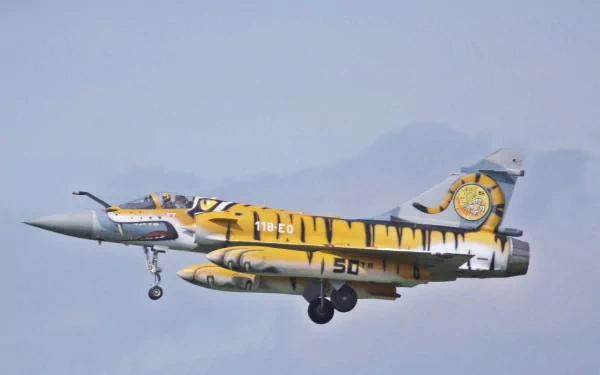 A Dassault Mirage 2000 military jet painted with a striking tiger design, flying against a clear sky, featured as an HD PC desktop wallpaper.