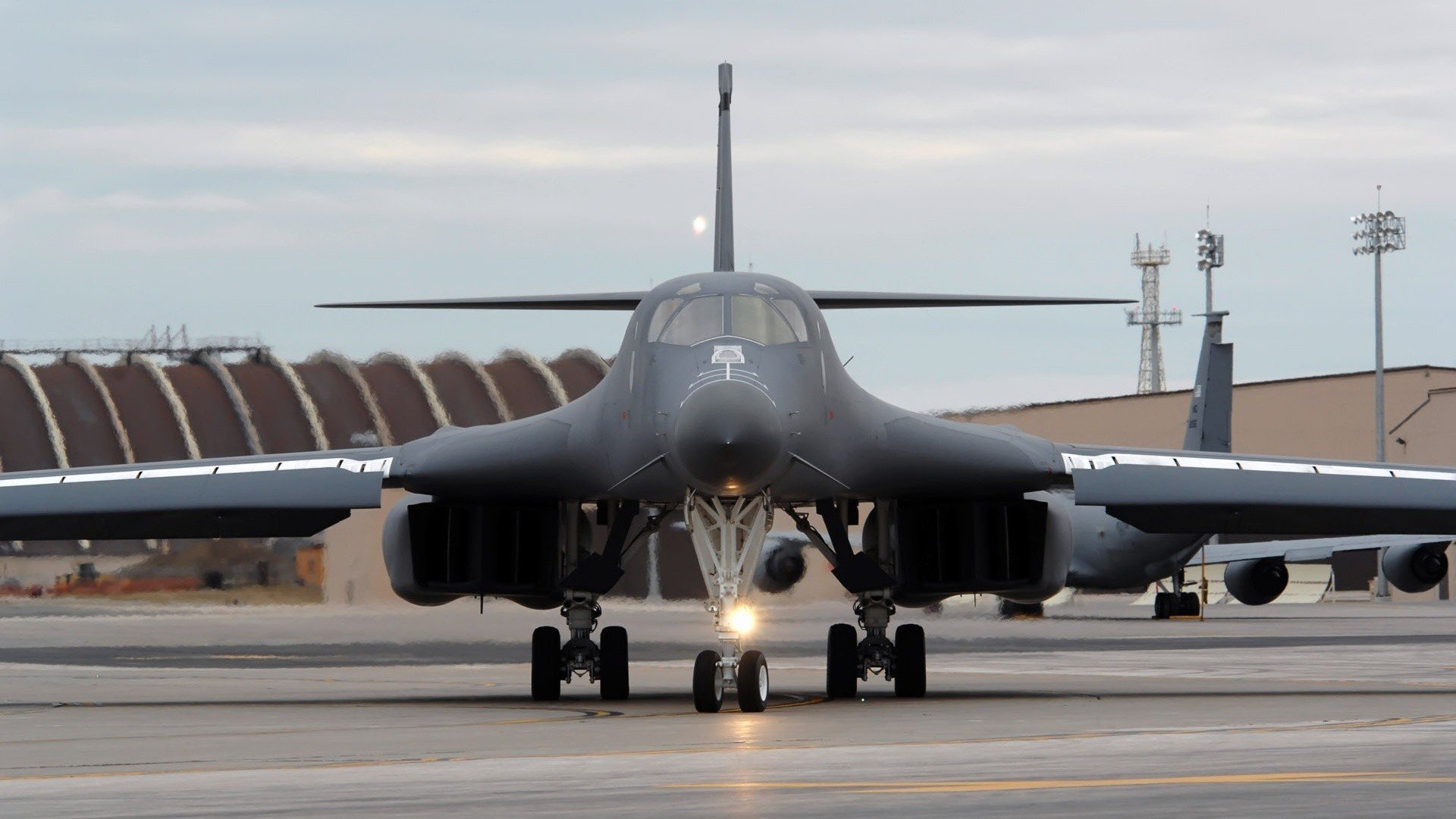 A high-definition desktop wallpaper showcasing a military aircraft on a runway, with a dramatic view of its imposing front and wings.