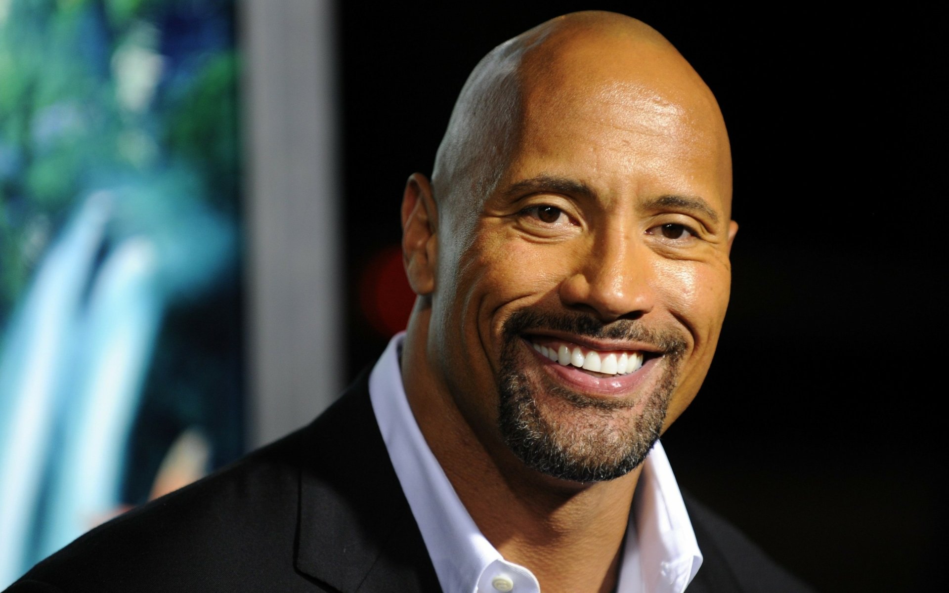 HD desktop wallpaper featuring a close-up of celebrity Dwayne Johnson smiling warmly against a blurred background.