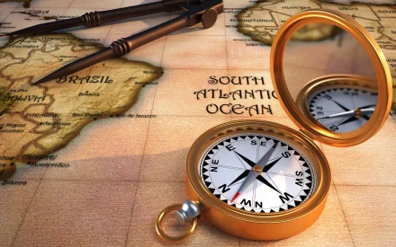 HD desktop wallpaper of a man-made compass resting on an antique map showing the South Atlantic Ocean, with drafting tools nearby.