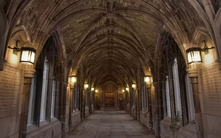 A stunning HD desktop wallpaper featuring a beautifully arched corridor at Cornell University, illuminated by vintage lanterns and showcasing intricate stonework.