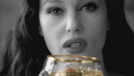 Monica Bellucci gazes intently while holding a golden-rimmed glass, set against a striking black-and-white background in this HD desktop wallpaper.
