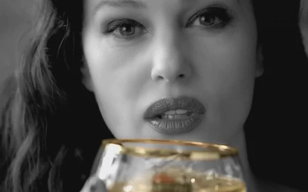 Monica Bellucci gazes intently while holding a golden-rimmed glass, set against a striking black-and-white background in this HD desktop wallpaper.