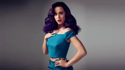 HD desktop wallpaper featuring music artist Katy Perry in a stylish teal outfit, with dark, wavy hair and vibrant makeup, posing against a neutral background.