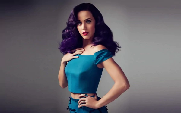 HD desktop wallpaper featuring music artist Katy Perry in a stylish teal outfit, with dark, wavy hair and vibrant makeup, posing against a neutral background.