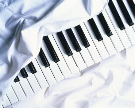 A close-up of piano keys partially covered by white fabric, creating a soft, artistic composition. This HD desktop wallpaper celebrates the elegance of music.