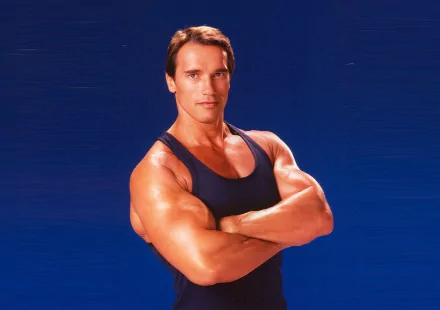 A muscular Arnold Schwarzenegger poses confidently against a blue background, making for an impactful HD desktop wallpaper and background.