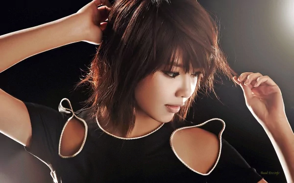 HD desktop wallpaper featuring an Asian woman with medium-length hair, looking down, wearing a black top with cut-out shoulders against a dark background.
