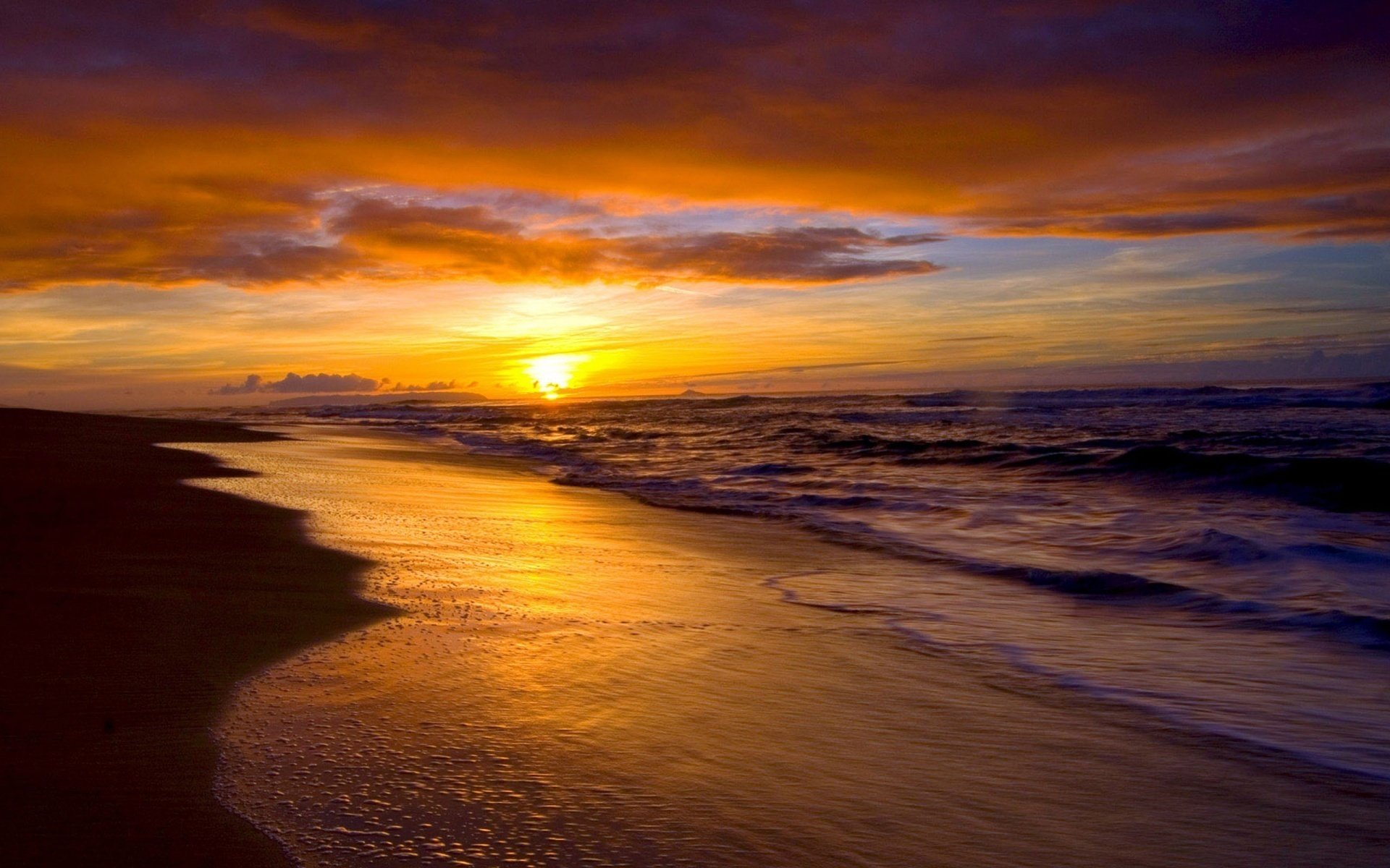 A stunning sunset over a tranquil ocean, with golden hues reflecting on the wet beach, merging horizon and clouds in this captivating nature scene. HD desktop wallpaper.