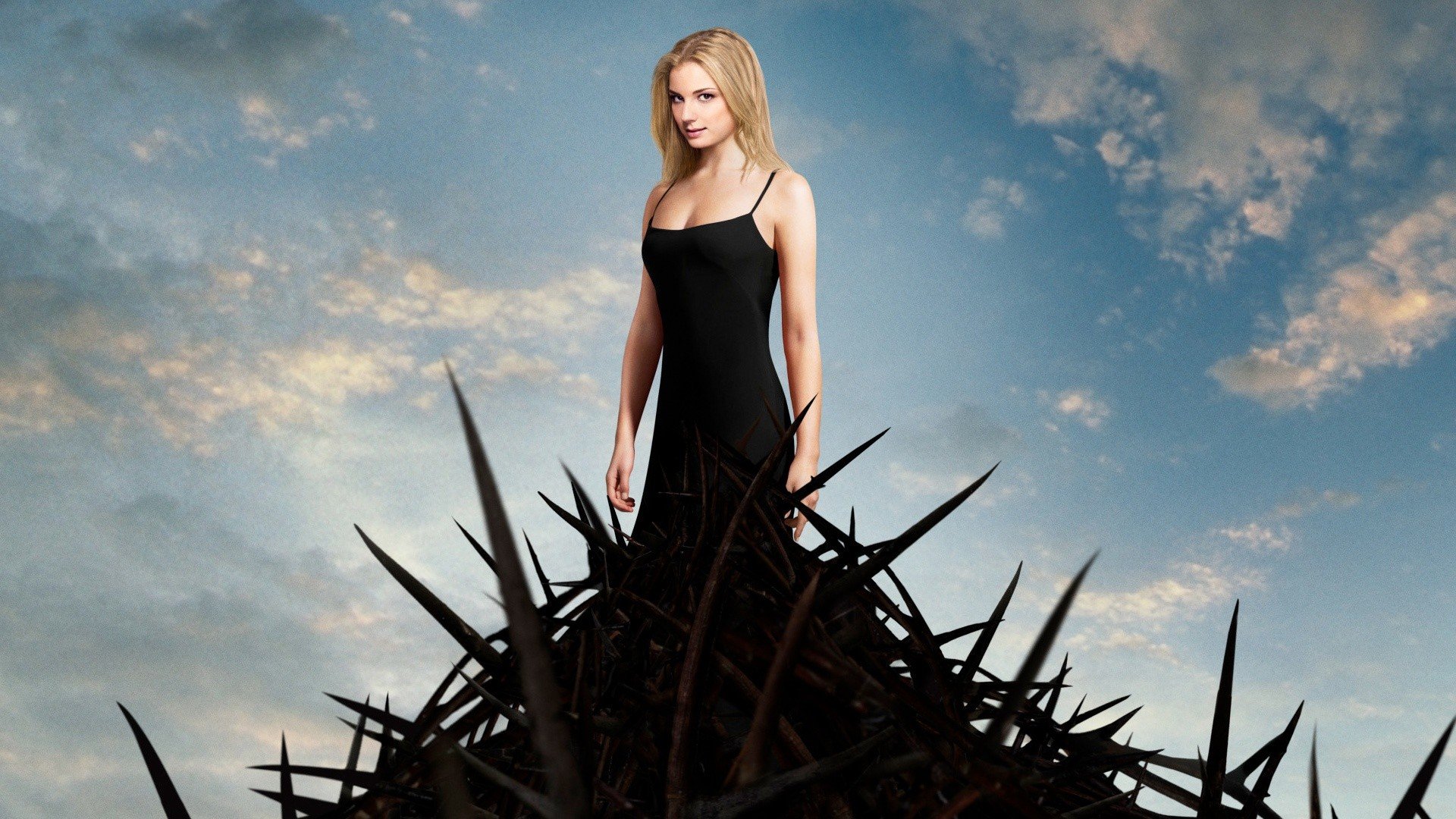 Emily VanCamp stands gracefully in a black dress against a dramatic sky, surrounded by dark, sharp thorns in this HD desktop wallpaper featuring the celebrity.
