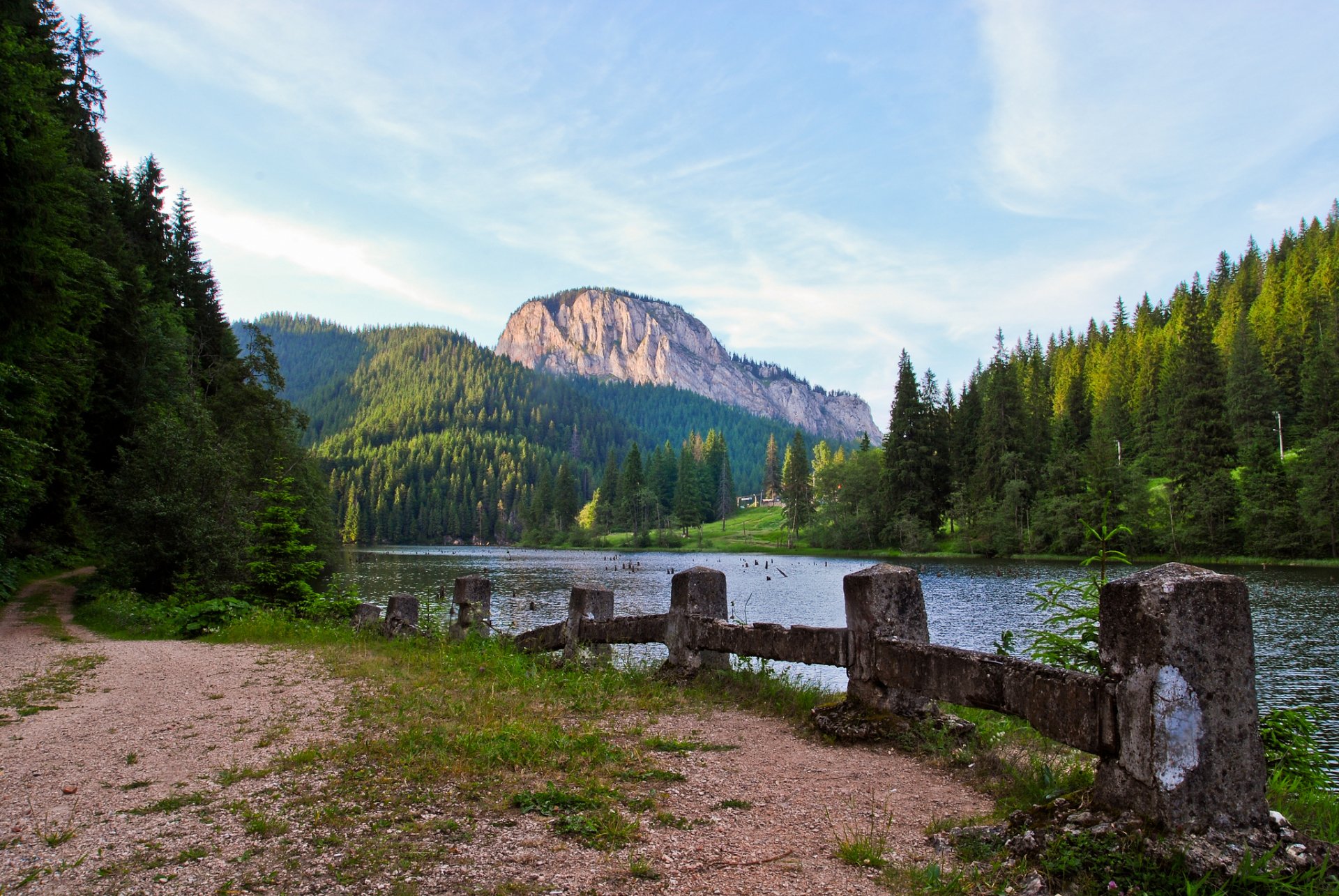 HD PC desktop wallpaper featuring a serene river flowing through a dense forest with a mountain backdrop under a clear blue sky.