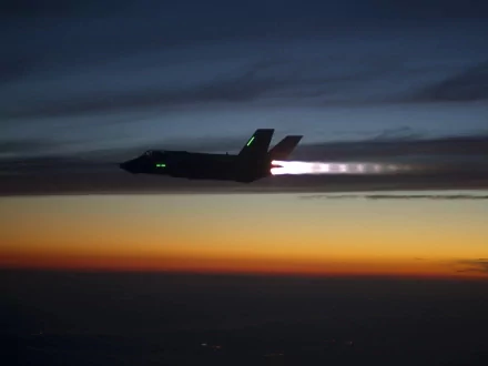 HD desktop wallpaper of a Lockheed Martin F-35 Lightning II jet soaring at dusk with afterburners glowing against a twilight sky.