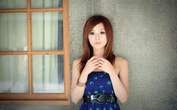 HD desktop wallpaper featuring a woman named Mikako Zhang Kaijie against a textured wall beside a window, wearing a blue dress with green star patterns and a black belt.