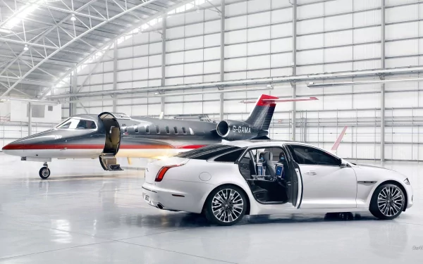 White Jaguar XJ Ultimate with rear-hinged door open beside a private jet in a glossy hangar — HD PC desktop wallpaper and background.